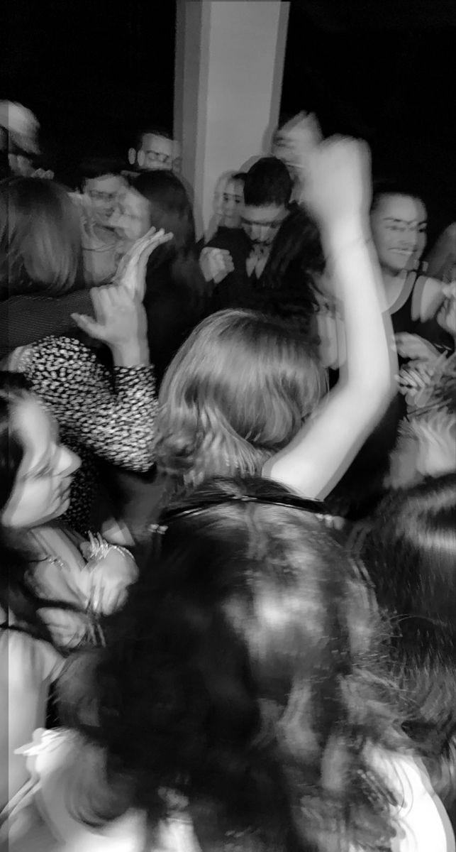 This may contain: black and white photograph of people dancing at a party with their hands in the air
