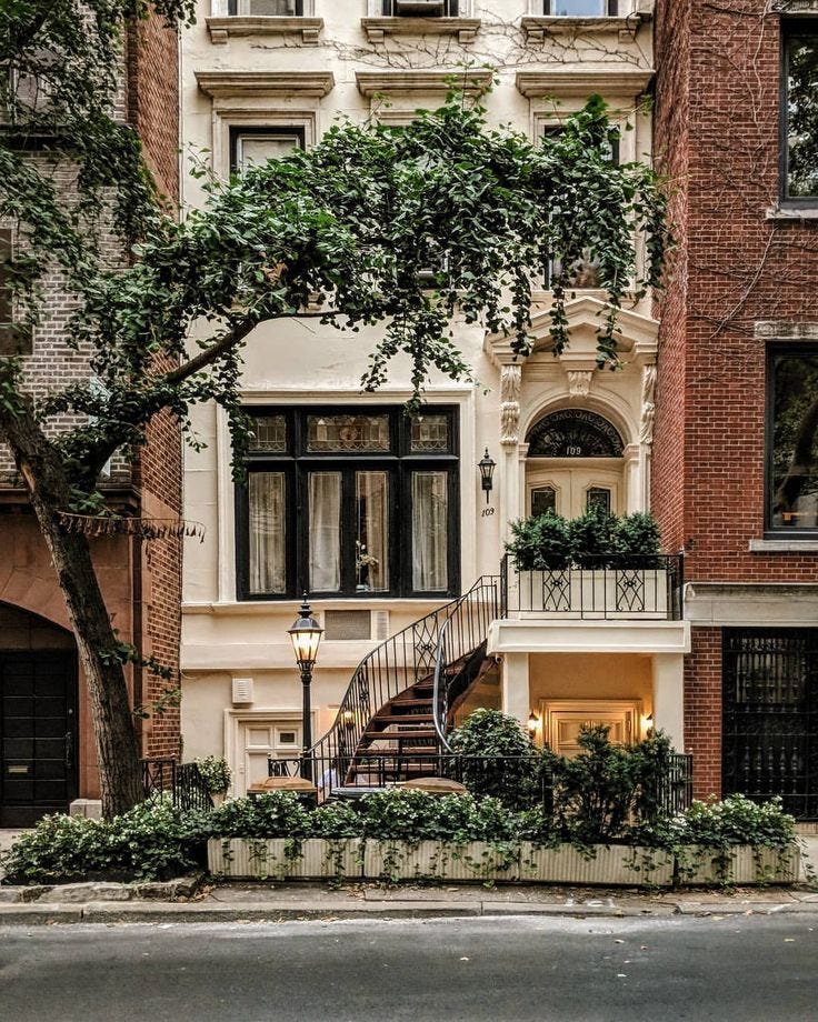 This may contain: an apartment building with stairs leading up to the second story and trees in front of it